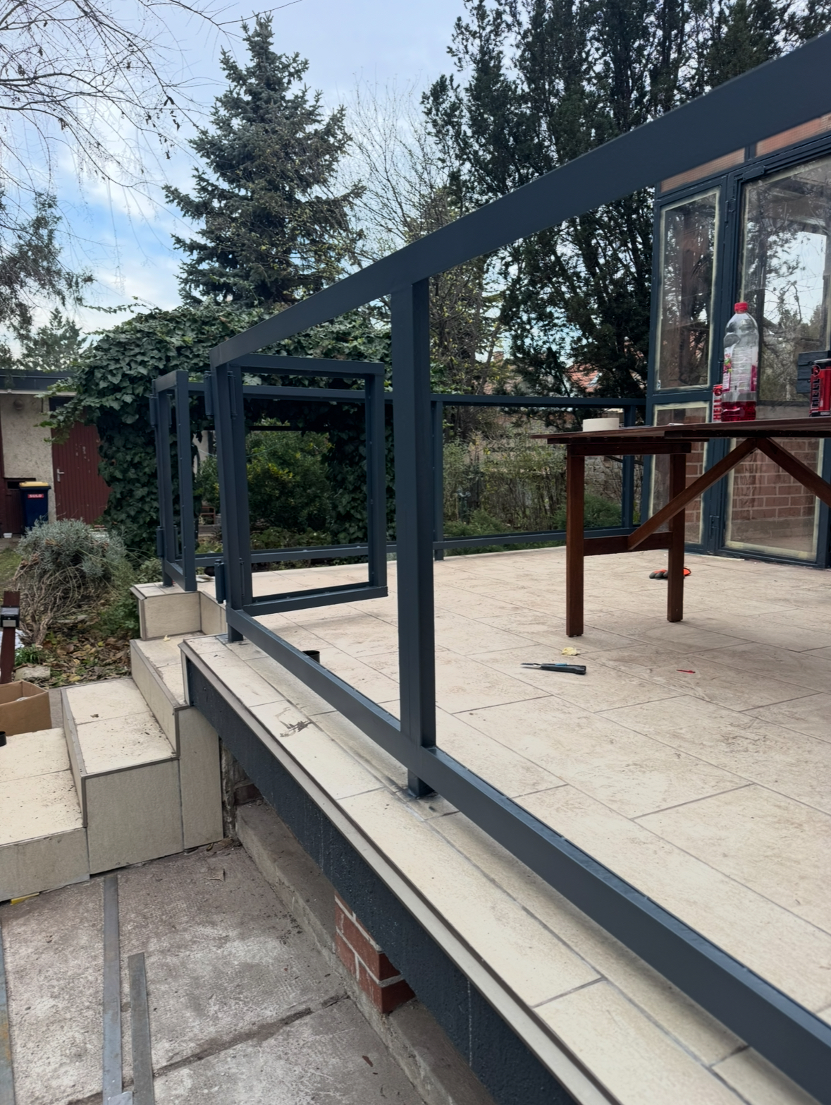 Egyedi korlátszerkezet gyártása és helyszíni telepítése teraszon. A munkafolyamat saját tervezésű acél korlátrendszer kialakításával indult, amelyet pontos méretvétel alapján gyártottunk le. A képen a frissen rögzített fémszerkezet látható, amely előkészítés alatt áll az üvegmezők beépítéséhez. A stabil alapozás és a precíz rögzítési pontok biztosítják, hogy az elkészült üvegezett korlát hosszú távon is biztonságos, időtálló és esztétikus megoldást nyújtson.